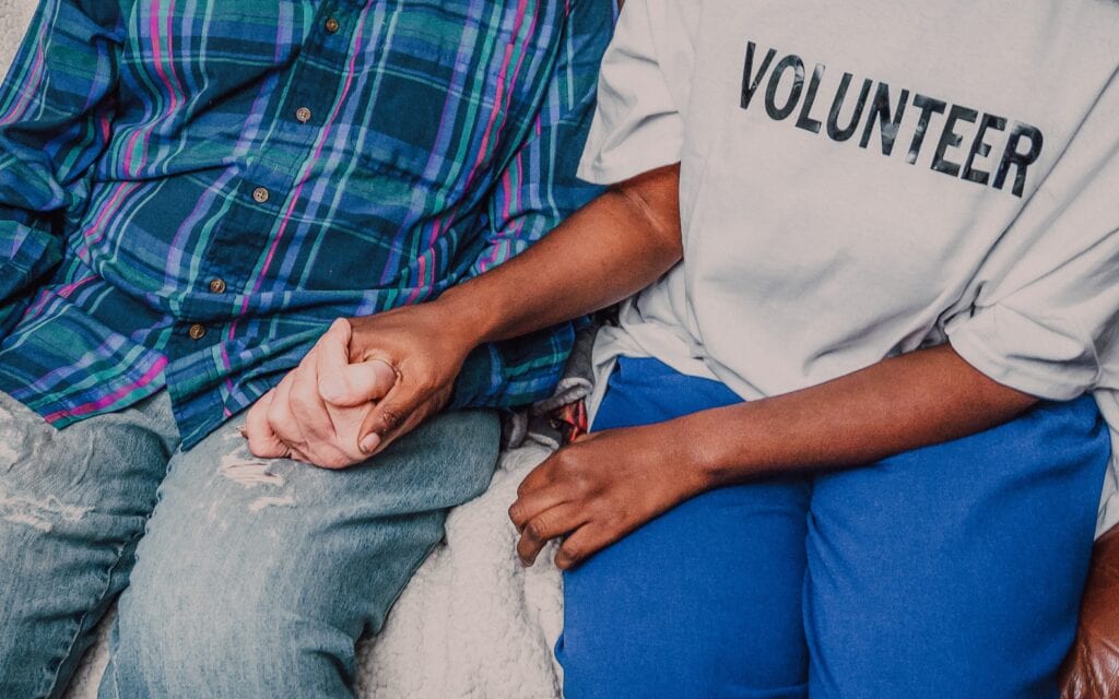 Une personne portant l'inscription "Volunteer" tient la main d'une autre personne. -emploi