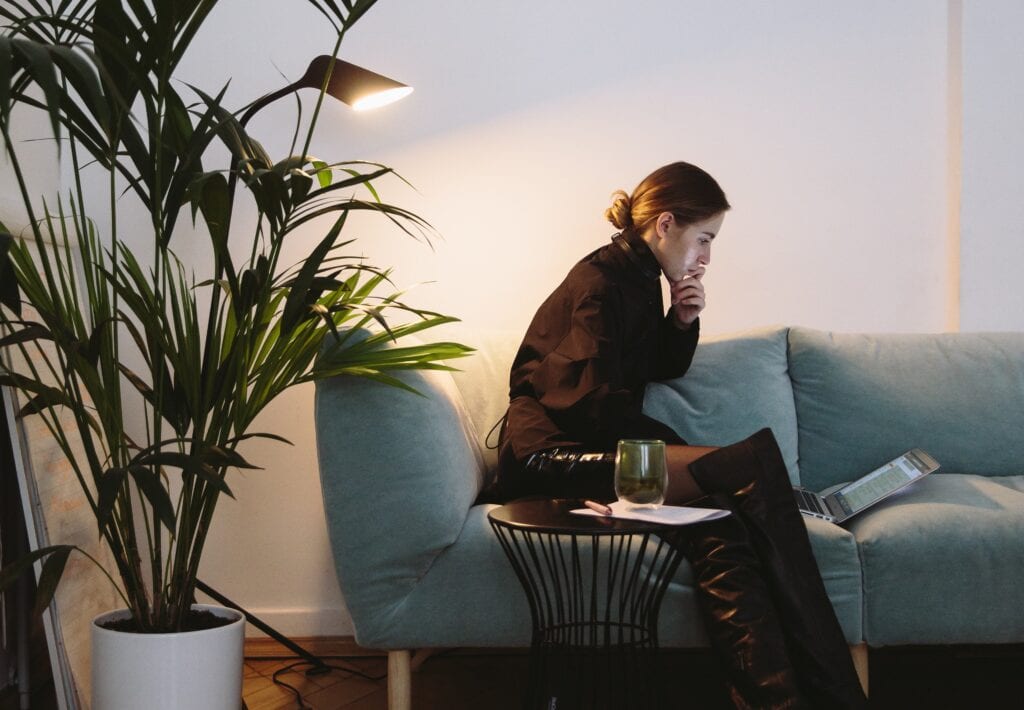 Une femme assise sur le canapé et travaillant dans un bureau à domicile